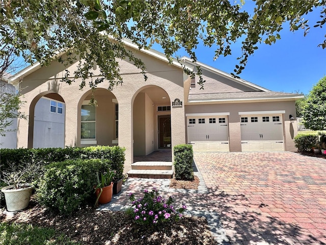 view of front of property with stucco siding, an attached garage, and decorative driveway