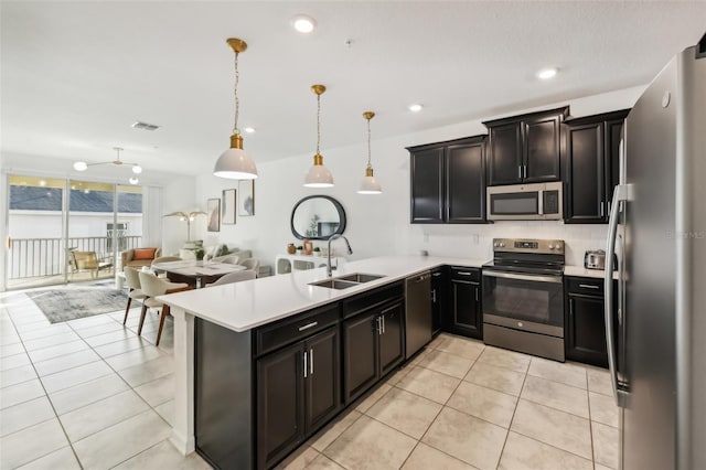 kitchen featuring kitchen peninsula, appliances with stainless steel finishes, sink, hanging light fixtures, and light tile patterned flooring