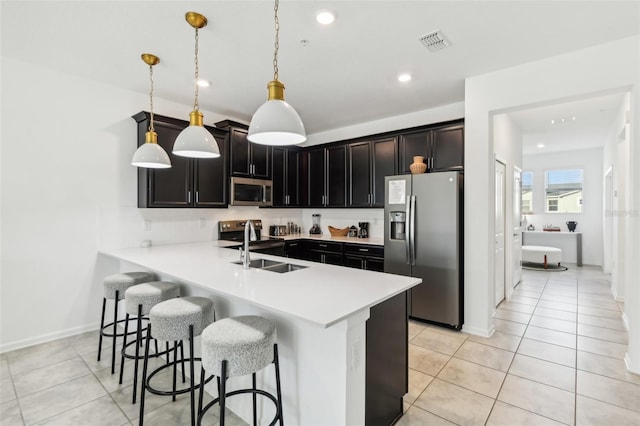 kitchen with kitchen peninsula, stainless steel appliances, sink, pendant lighting, and light tile patterned floors