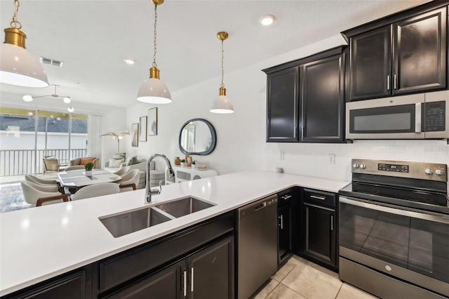 kitchen featuring appliances with stainless steel finishes, backsplash, sink, light tile patterned floors, and hanging light fixtures