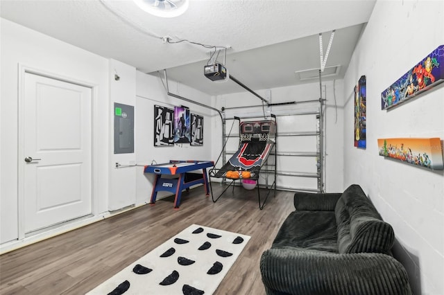 recreation room featuring electric panel, wood-type flooring, and a textured ceiling