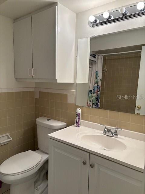 bathroom featuring curtained shower, vanity, tile walls, and toilet