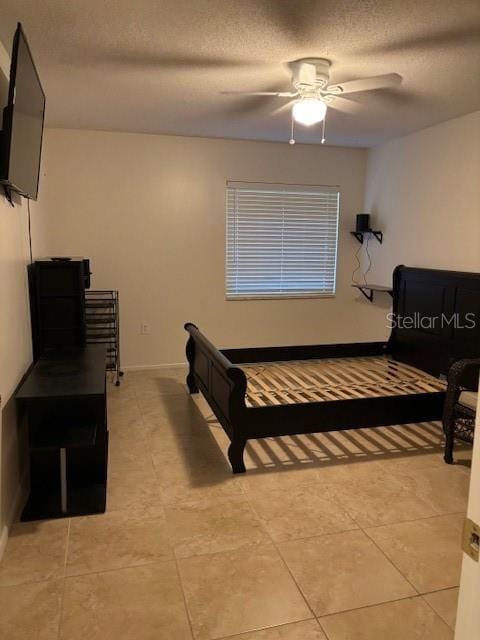 tiled bedroom with ceiling fan and a textured ceiling