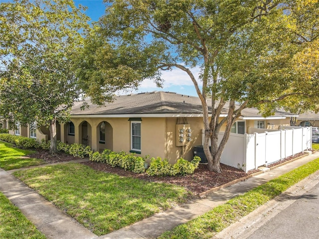 single story home with central AC, a front yard, fence, and stucco siding