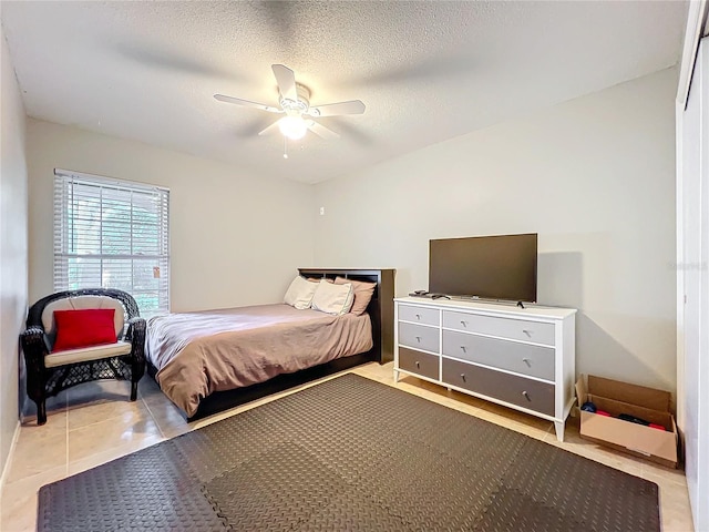 tiled bedroom featuring a ceiling fan and a textured ceiling