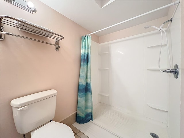 full bath featuring toilet, a stall shower, and tile patterned flooring