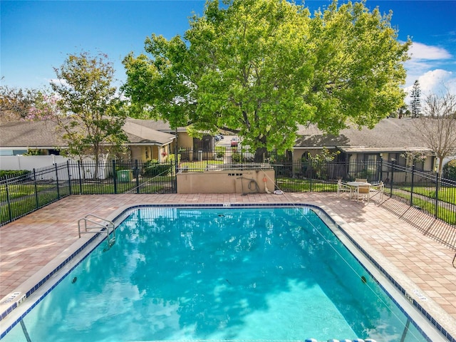 community pool with a patio, fence, and a residential view