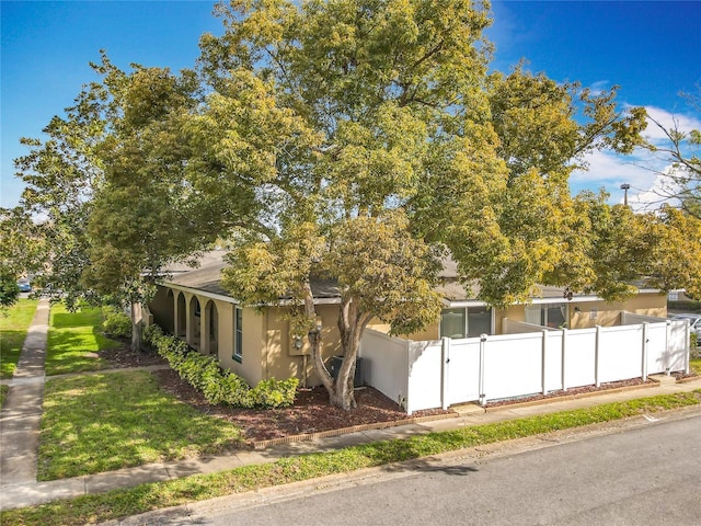 view of side of property with central AC unit, a lawn, a gate, fence, and stucco siding