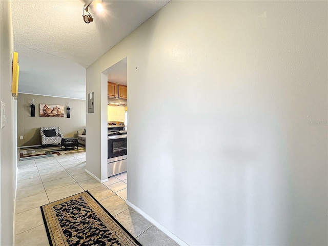 corridor with light tile patterned floors, a textured ceiling, and baseboards