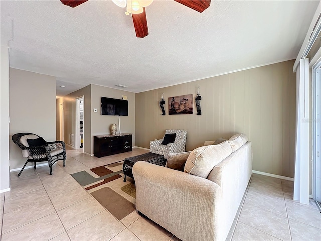 living area featuring light tile patterned floors, visible vents, baseboards, a ceiling fan, and a textured ceiling