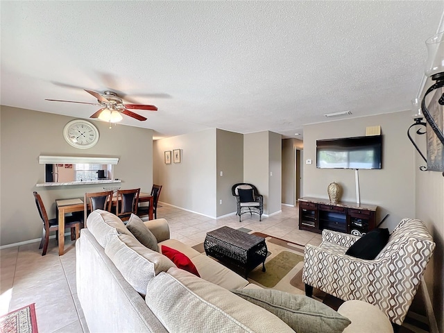 living room with baseboards, a ceiling fan, a textured ceiling, and light tile patterned flooring