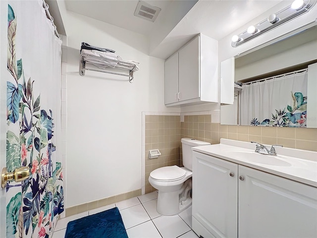 bathroom with visible vents, toilet, tile patterned floors, vanity, and tile walls