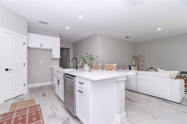 kitchen featuring a center island with sink, sink, stainless steel dishwasher, light hardwood / wood-style floors, and white cabinetry