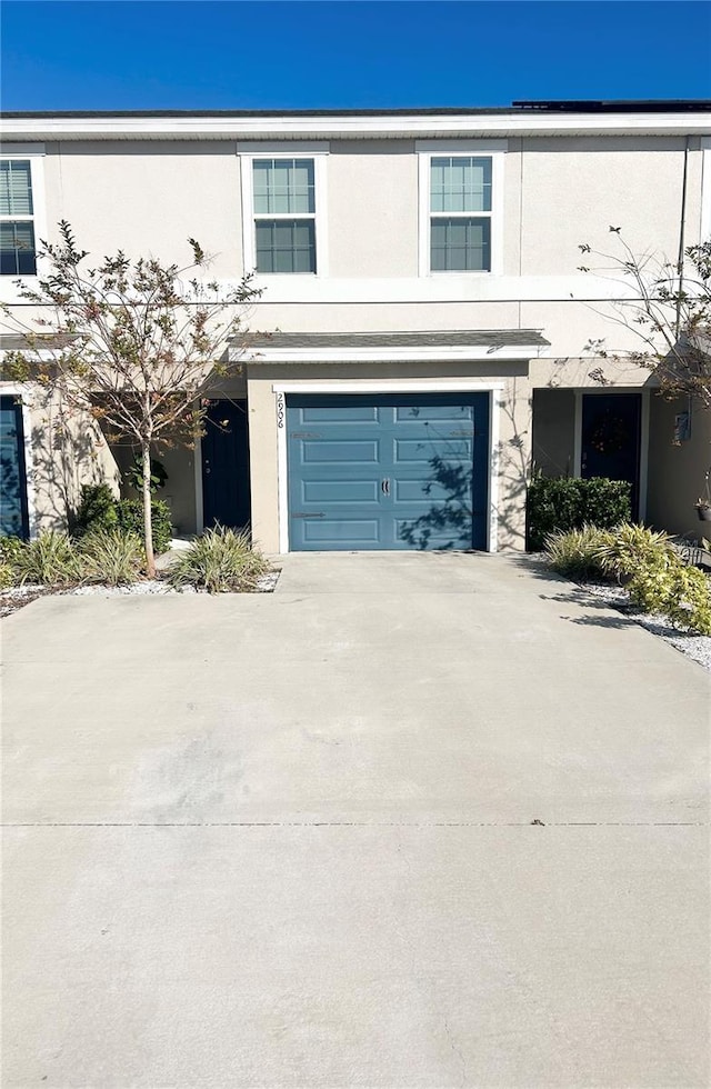 view of front facade with a garage, driveway, and stucco siding