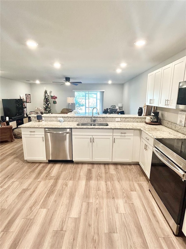 kitchen with sink, light hardwood / wood-style flooring, appliances with stainless steel finishes, white cabinetry, and kitchen peninsula