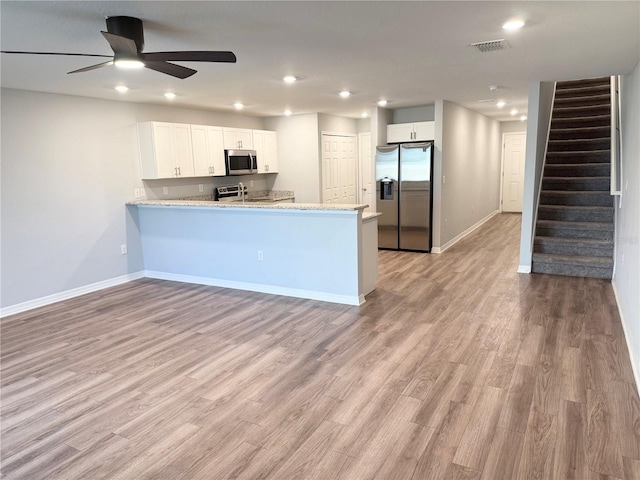 kitchen with a peninsula, light wood-style floors, white cabinetry, and appliances with stainless steel finishes