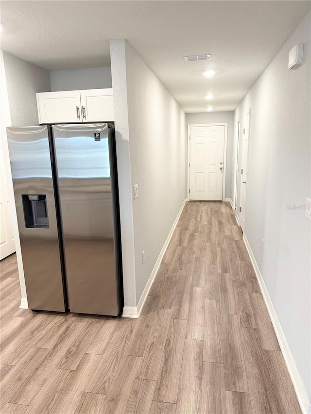 corridor featuring baseboards, visible vents, and light wood-style floors