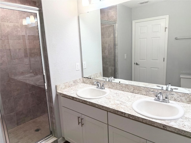 bathroom with a stall shower, a sink, toilet, and double vanity