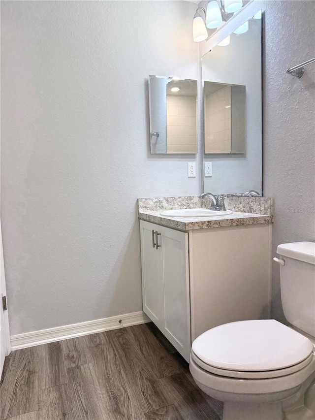 bathroom featuring baseboards, vanity, toilet, and wood finished floors