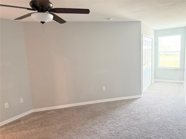 unfurnished room featuring a ceiling fan, light carpet, a textured ceiling, and baseboards