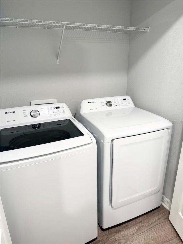 laundry room featuring laundry area, washing machine and dryer, and wood finished floors