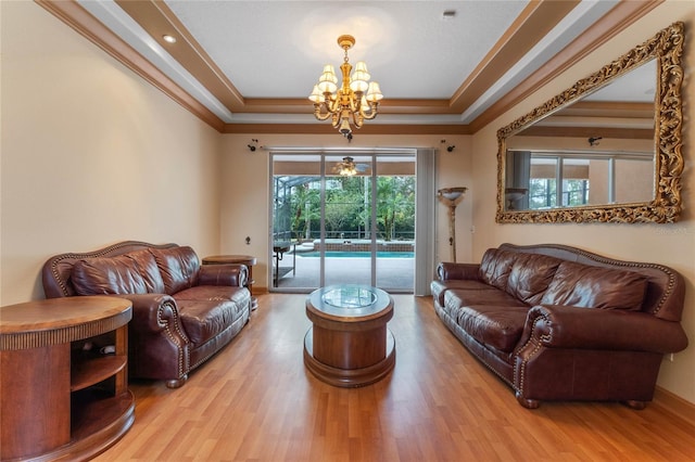 living room featuring hardwood / wood-style floors, a tray ceiling, crown molding, and a notable chandelier