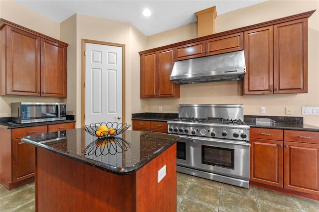 kitchen with stainless steel appliances, a kitchen island, and dark stone countertops