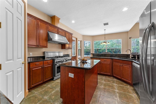 kitchen featuring a center island, sink, hanging light fixtures, stainless steel appliances, and a textured ceiling