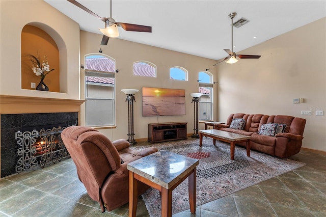 living room featuring ceiling fan, a healthy amount of sunlight, and a tiled fireplace