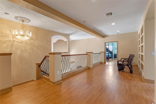 interior space with beamed ceiling, wood-type flooring, a textured ceiling, and an inviting chandelier