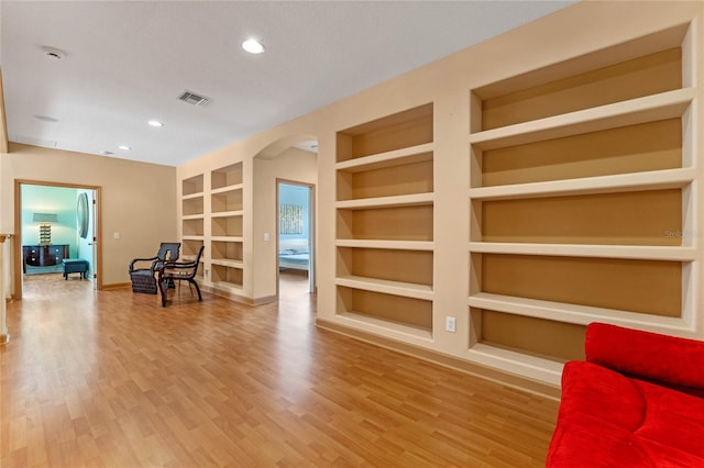 living area featuring hardwood / wood-style flooring, built in shelves, and a textured ceiling