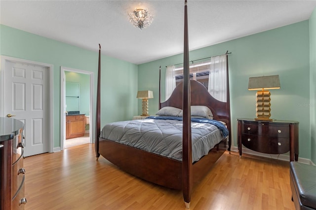 bedroom with a textured ceiling, connected bathroom, and light hardwood / wood-style flooring