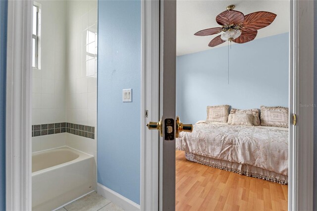 bathroom with wood-type flooring, a tub to relax in, and ceiling fan