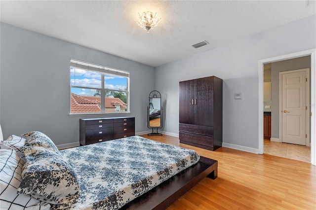 bedroom featuring a textured ceiling and light hardwood / wood-style flooring