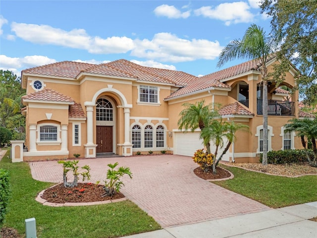 mediterranean / spanish home with a balcony, a front lawn, and a garage