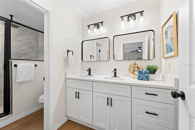 bathroom with ceiling fan, hardwood / wood-style floors, toilet, a shower with door, and vanity