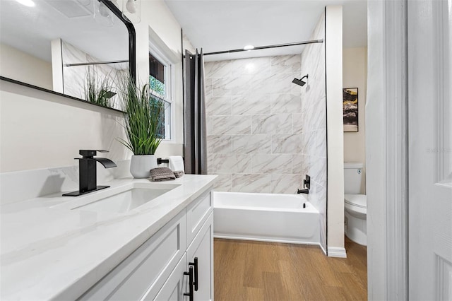 full bathroom featuring tiled shower / bath combo, toilet, wood-type flooring, and vanity