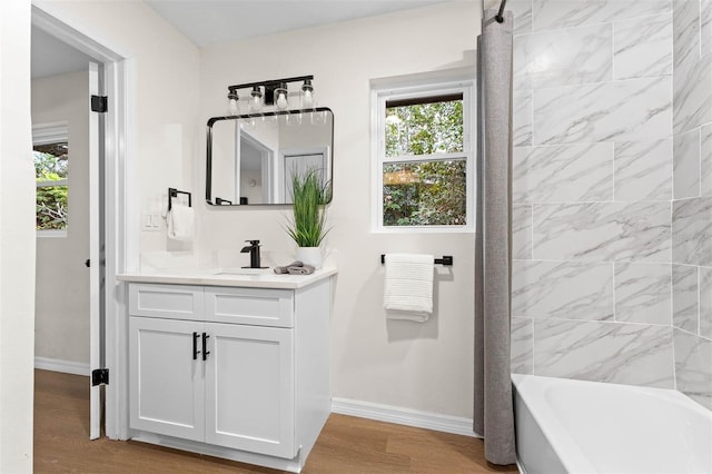 bathroom with hardwood / wood-style floors, vanity, and tiled shower / bath combo