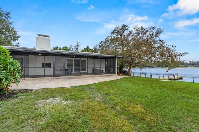 back of property with a sunroom, a water view, and a yard