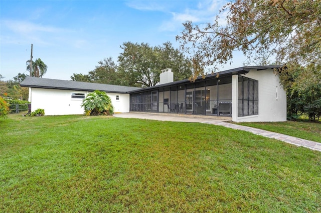 rear view of property featuring a yard and a sunroom