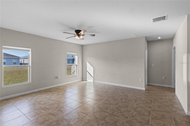 tiled empty room featuring ceiling fan