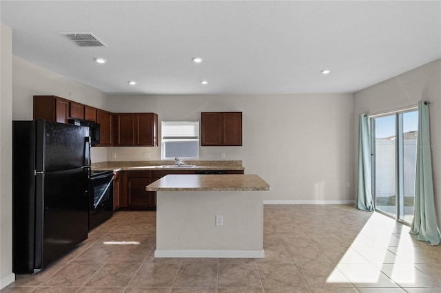 kitchen featuring black appliances, plenty of natural light, a kitchen island, and light tile patterned flooring