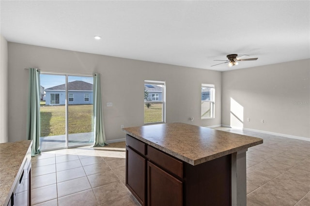 kitchen with ceiling fan, a center island, light tile patterned flooring, and a wealth of natural light