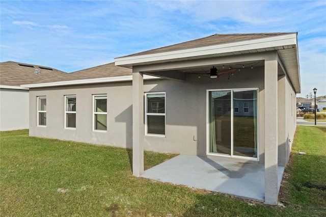 rear view of house featuring ceiling fan, a yard, and a patio