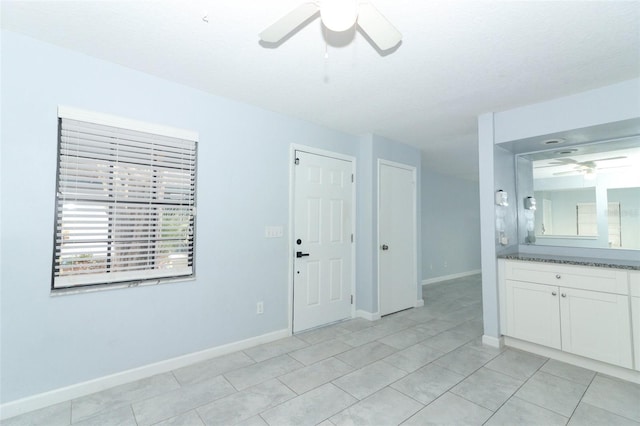 tiled empty room with ceiling fan and a textured ceiling