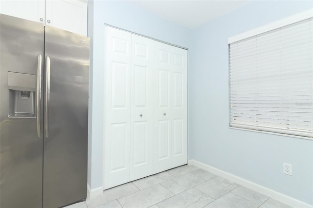 interior space with stainless steel fridge, a closet, and light tile patterned flooring