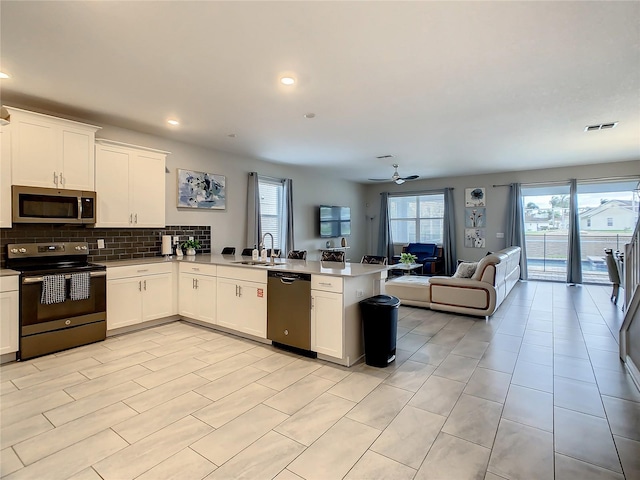 kitchen with sink, kitchen peninsula, ceiling fan, white cabinetry, and stainless steel appliances