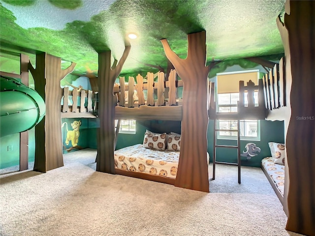 carpeted bedroom with a textured ceiling and multiple windows