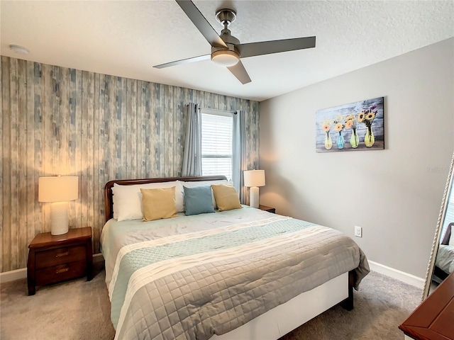 carpeted bedroom with ceiling fan, wood walls, and a textured ceiling