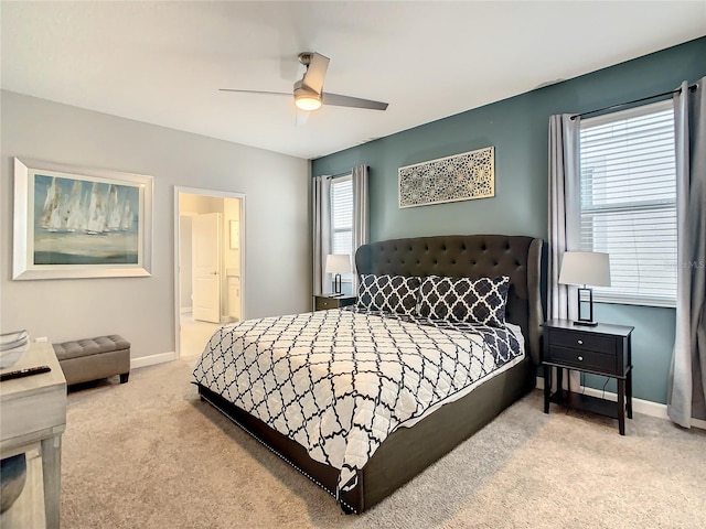 bedroom featuring ceiling fan, light colored carpet, and connected bathroom